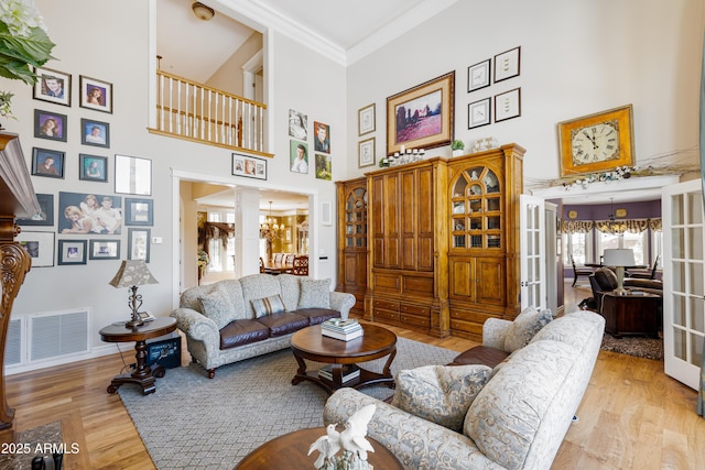 living room with visible vents, ornamental molding, decorative columns, and wood finished floors