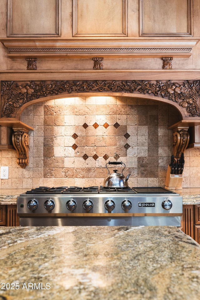 details featuring light stone counters, brown cabinetry, backsplash, and stainless steel gas cooktop