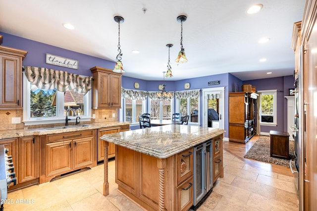 kitchen with decorative backsplash, light stone counters, a center island, and a sink