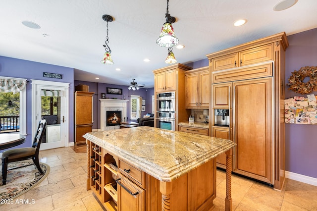 kitchen featuring a kitchen island, stainless steel double oven, baseboards, paneled built in refrigerator, and light stone countertops