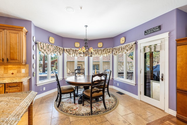 dining space with visible vents, baseboards, an inviting chandelier, and stone tile floors
