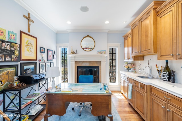 office with a glass covered fireplace, crown molding, light wood-type flooring, and a sink