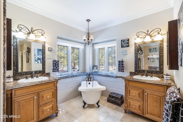bathroom featuring a notable chandelier, ornamental molding, two vanities, and a sink