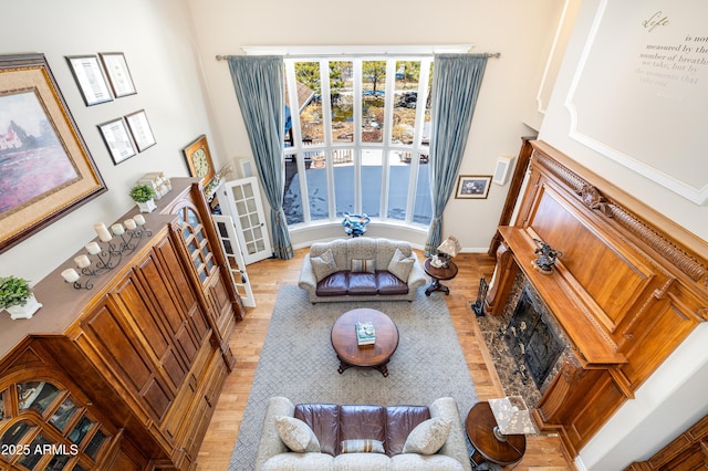 living area featuring a fireplace with flush hearth, wood finished floors, and baseboards