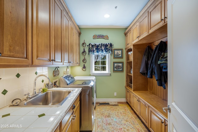 laundry area featuring a sink, baseboards, cabinet space, and independent washer and dryer