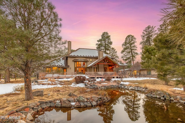 back of property with a wooden deck and a chimney