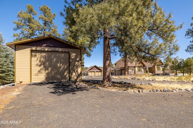 view of front of house with an outdoor structure, a detached garage, and aphalt driveway