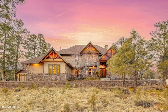 craftsman-style house featuring stone siding, a garage, a chimney, and roof with shingles