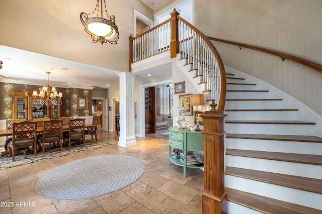 stairs featuring a notable chandelier, stone tile flooring, recessed lighting, decorative columns, and a towering ceiling