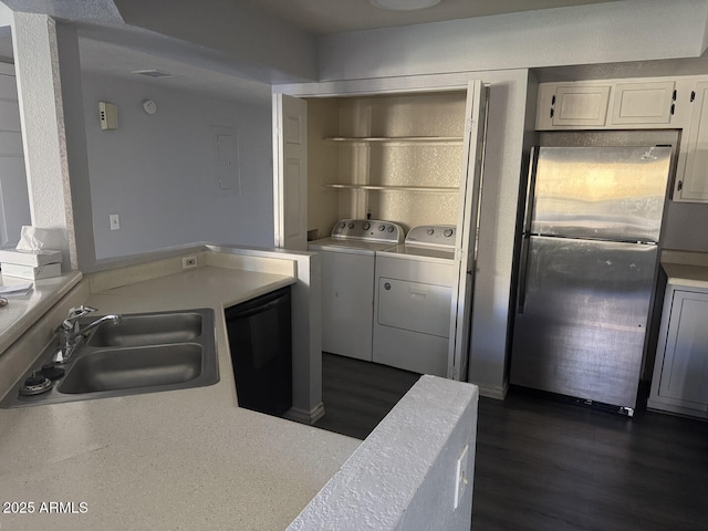 kitchen with refrigerator, sink, washing machine and dryer, white cabinetry, and stainless steel refrigerator