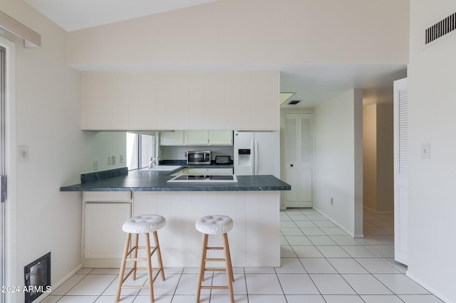 kitchen featuring a breakfast bar, sink, white fridge with ice dispenser, and kitchen peninsula