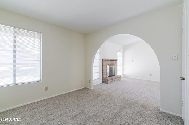 unfurnished living room with a fireplace, a wealth of natural light, and light carpet