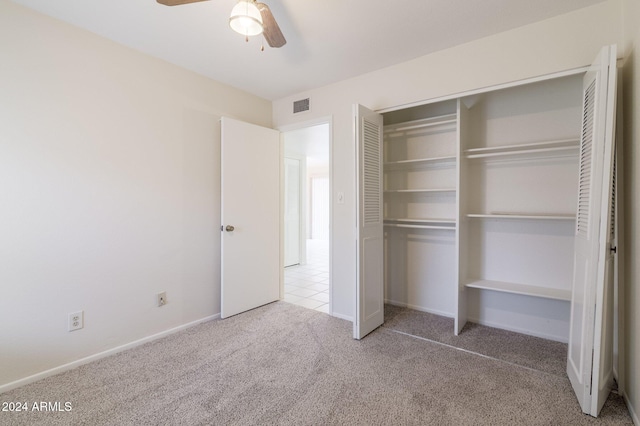 unfurnished bedroom featuring ceiling fan, light colored carpet, and a closet