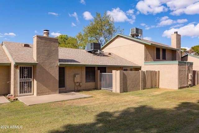 rear view of house featuring central AC unit, a patio area, and a lawn