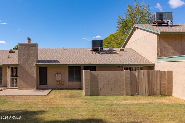 rear view of property with central air condition unit, a lawn, and a patio