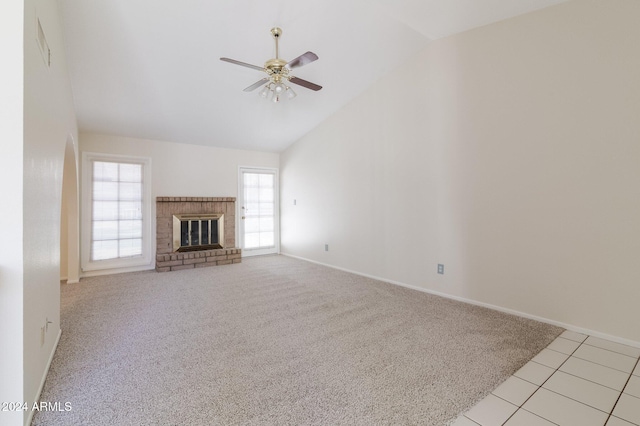 unfurnished living room with a brick fireplace, light carpet, ceiling fan, and vaulted ceiling