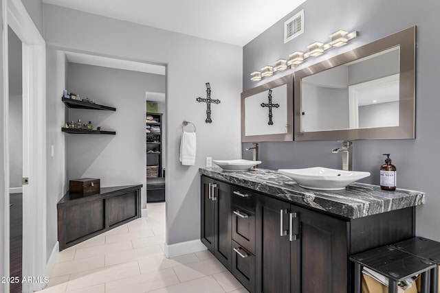 bathroom with baseboards, double vanity, and tile patterned flooring