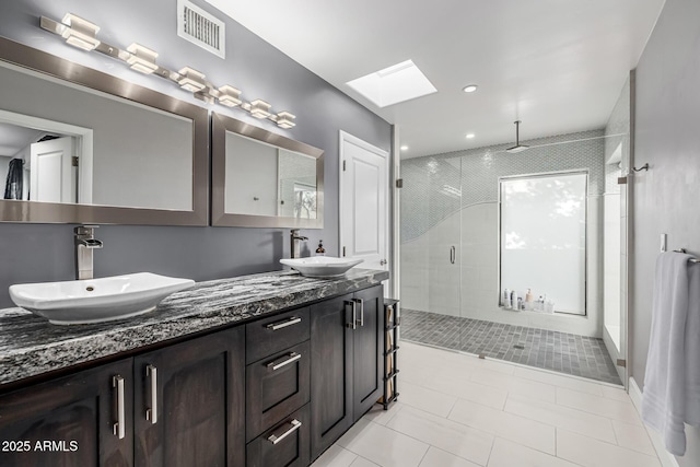 full bathroom featuring a skylight, a stall shower, tile patterned floors, and double vanity
