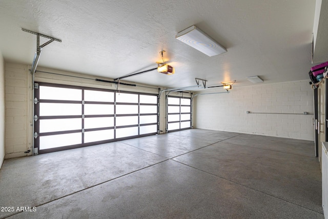garage with a garage door opener and concrete block wall