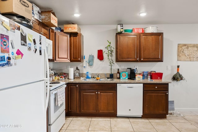 kitchen featuring light stone countertops, white appliances, sink, and light tile patterned floors