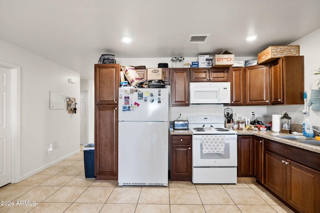 kitchen featuring light stone countertops, sink, light tile patterned flooring, and white appliances