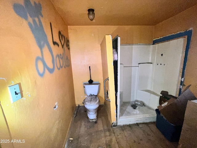 bathroom featuring wood finished floors, a shower stall, and toilet