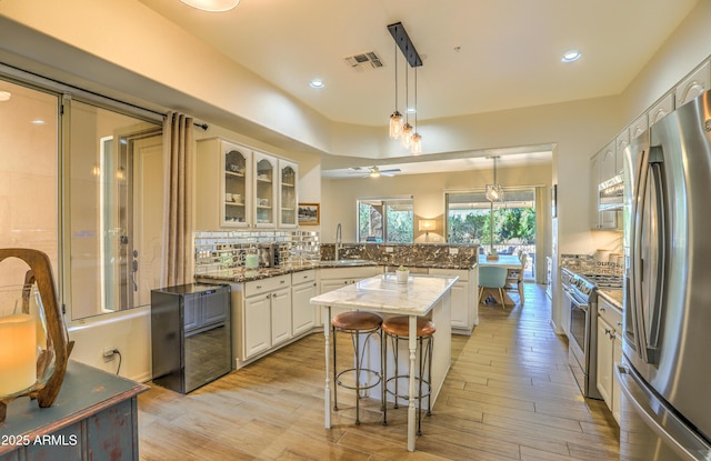 kitchen with sink, hanging light fixtures, stainless steel appliances, a center island, and light stone counters