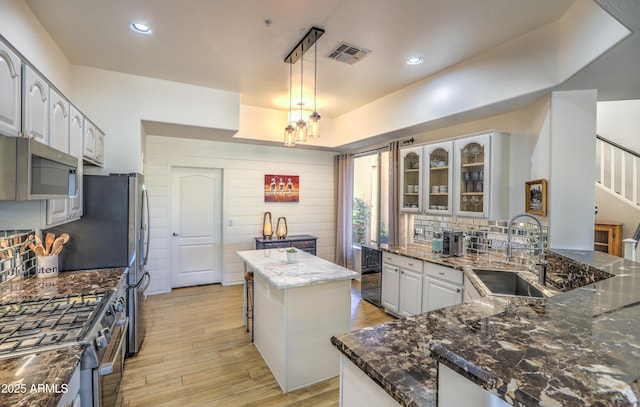 kitchen with sink, decorative light fixtures, a center island, dark stone counters, and stainless steel appliances