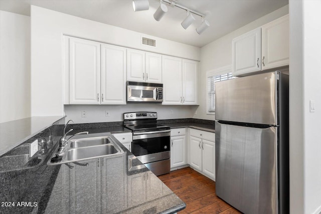 kitchen featuring dark wood-type flooring, track lighting, white cabinets, sink, and appliances with stainless steel finishes