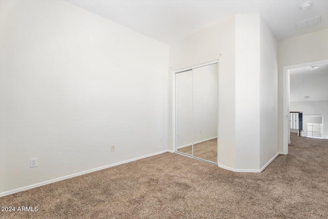 unfurnished bedroom featuring light carpet and a closet