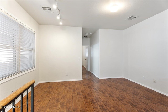 spare room featuring rail lighting and dark wood-type flooring