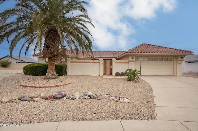 view of front of house featuring a fenced front yard, a tile roof, stucco siding, a garage, and driveway