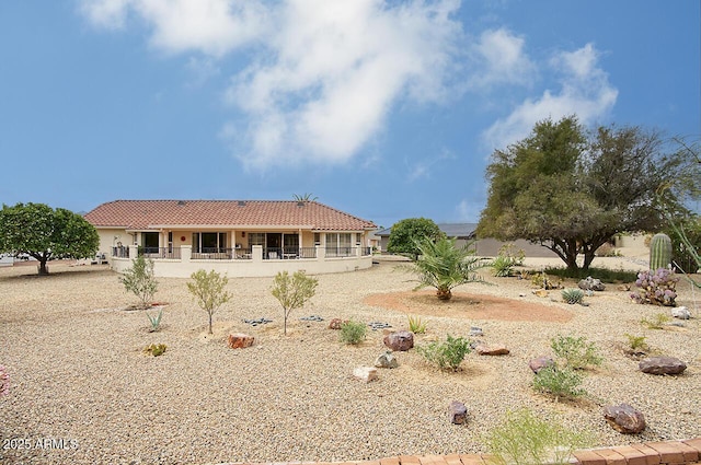 rear view of house with stucco siding and a tile roof