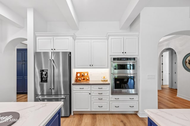 1948 W Paso Trl, Phoenix, AZ 85085 - kitchen with appliances with stainless steel finishes, arched walkways, light wood-style flooring, and decorative backsplash