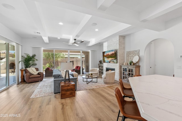 1948 W Paso Trl, Phoenix, AZ 85085 - living room featuring beamed ceiling, ceiling fan, light wood-style floors, a fireplace, and arched walkways