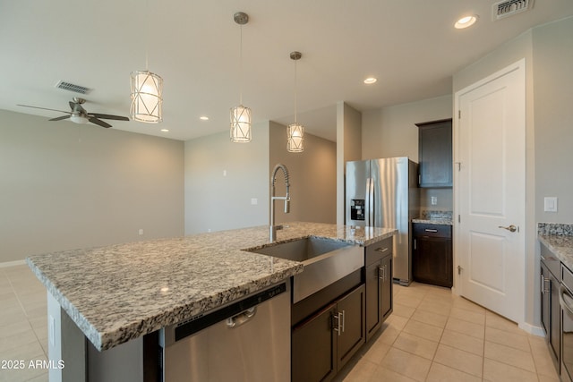kitchen with light tile patterned floors, a kitchen island with sink, a sink, and stainless steel appliances