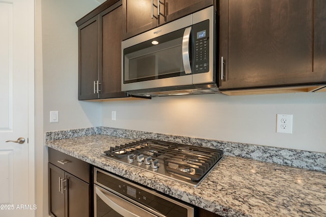 kitchen featuring dark brown cabinetry, stainless steel appliances, and light stone countertops