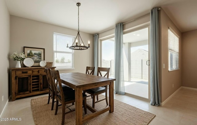 dining space featuring light tile patterned floors, a notable chandelier, and baseboards