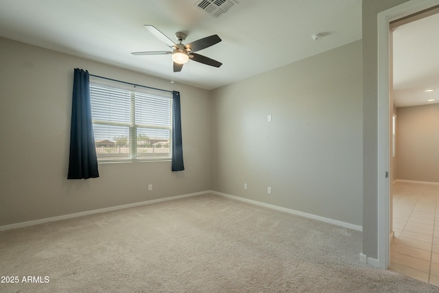 spare room with visible vents, ceiling fan, light carpet, and baseboards