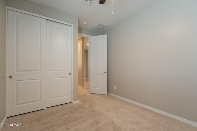 unfurnished bedroom featuring light colored carpet, a closet, baseboards, visible vents, and a ceiling fan