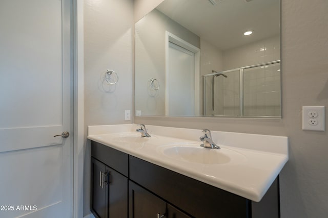 bathroom with double vanity, tiled shower, and a sink