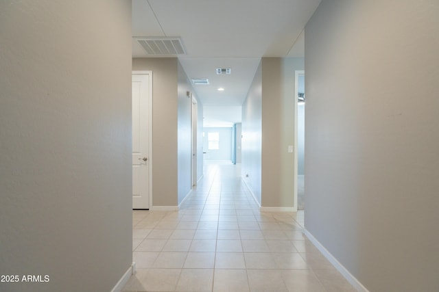 hall featuring light tile patterned floors, visible vents, and baseboards