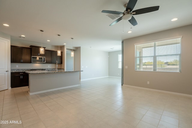 kitchen featuring stainless steel microwave, dark brown cabinets, baseboards, open floor plan, and recessed lighting