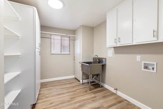 clothes washing area featuring cabinet space, baseboards, gas dryer hookup, light wood-style flooring, and hookup for a washing machine