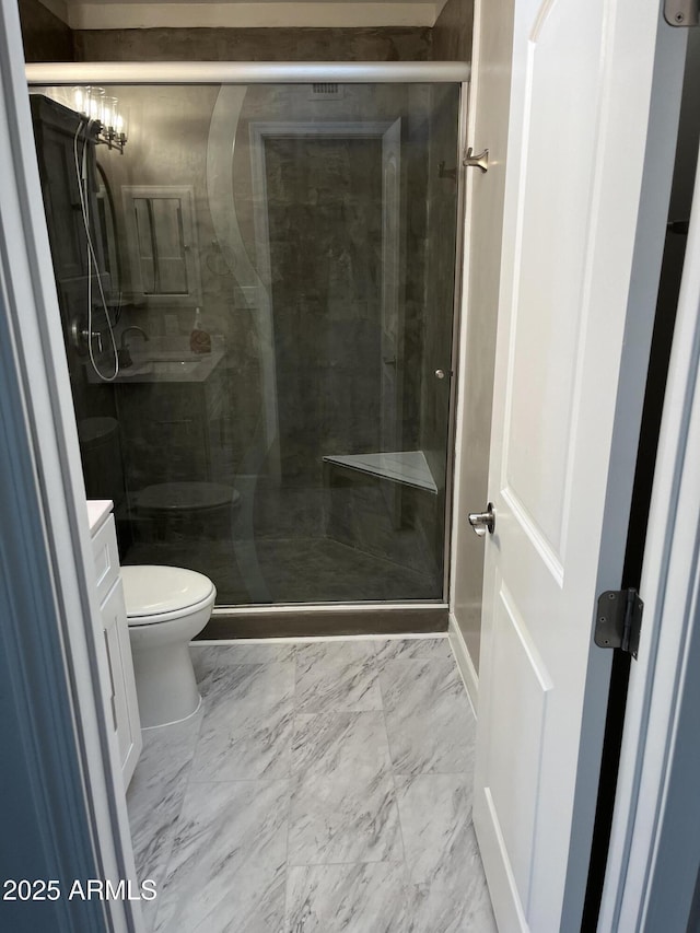 bathroom with marble finish floor, vanity, a shower stall, and toilet