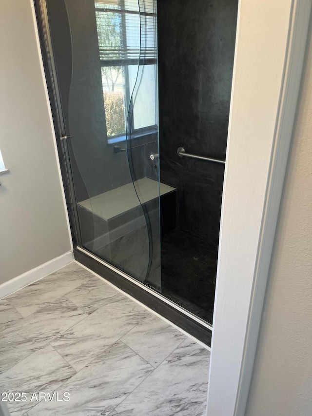 full bathroom with marble finish floor, baseboards, and a stall shower