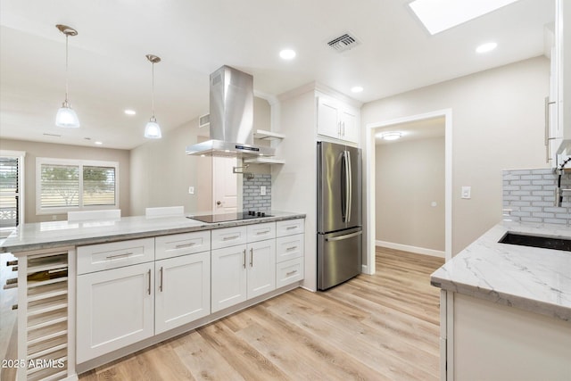 kitchen featuring island exhaust hood, visible vents, freestanding refrigerator, beverage cooler, and black electric cooktop