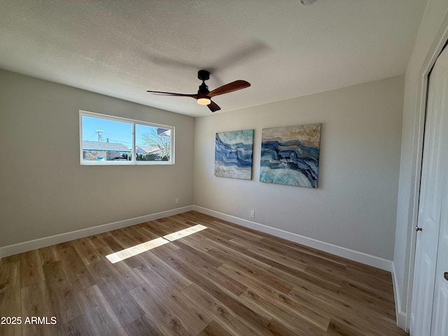 unfurnished bedroom with baseboards, wood finished floors, a closet, a textured ceiling, and a ceiling fan