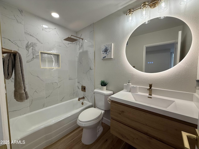 full bath featuring toilet, wood finished floors, vanity, shower / bathtub combination, and a textured wall