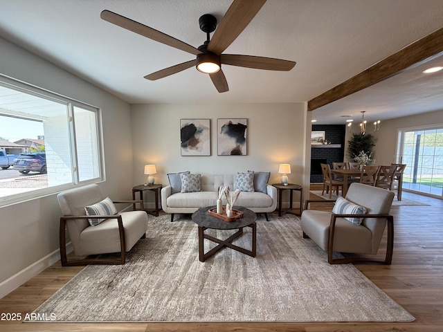 living room featuring ceiling fan, beamed ceiling, baseboards, and wood finished floors